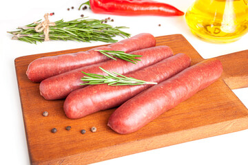 Raw meat beef sausages for grill and spicy, herbs rosemary, pepper, salt on table