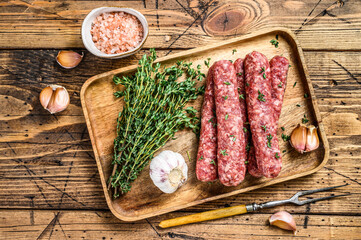 Homamade raw mince meat  sausages on a cutting board. wooden background. Top view