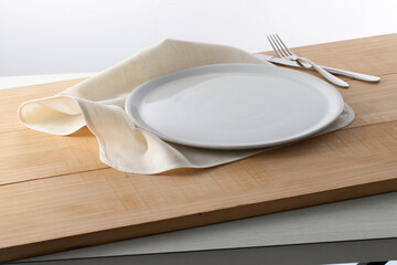 Loza blanca, plato y cubiertos sobre madera. White crockery, plate and cutlery on wood.