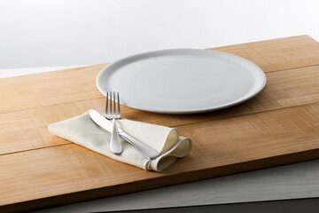 Menaje plato y cubiertos sobre mesa de madera, vista cenital. Kitchenware plate and cutlery on...
