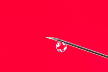 Reflection of the flag of Great Britain in a little drop on the top of the needle. Concept of vaccination against Covid-19 virus.