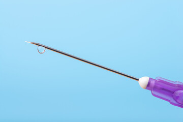 Top of the syringe with a needle and little drop on it on the blue background. Concept of vaccination against coronavirus, making an injection.