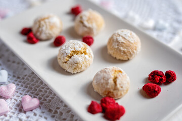 baked low sugar vegan coconut crincle cookies bisquits on a romantic crochet white  table cloth with freeze dried raspberries