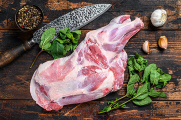 Whole Raw lamb shoulder leg meat with garlic, mint. Dark wooden background. Top view