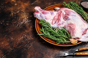 Whole fresh Raw lamb shoulder meat on a plate. Dark wooden background. Top view. Copy space