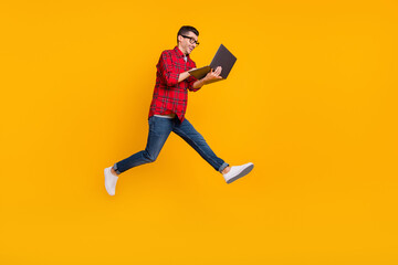 Fototapeta na wymiar Full size profile side photo of young happy man in glasses run in air working in laptop isolated on yellow color background
