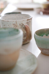 Turquoise handmade cups. Kitchen tea set on a white table. Minimalistic set of dishes