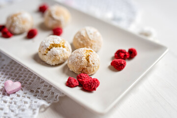 baked low sugar vegan coconut crincle cookies bisquits on a romantic crochet white  table cloth with freeze dried raspberries
