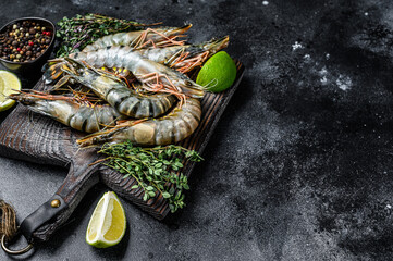 Raw black tiger prawns, shrimps and spices.  Black background. Top view. Copy space