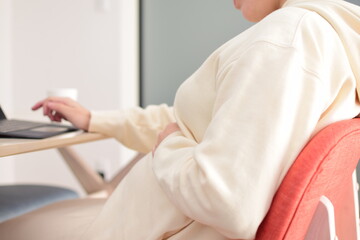 A pregnant woman in her twenties works from home using a laptop with fear of coronavirus and flu virus.