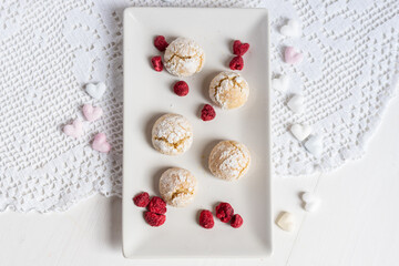 baked low sugar vegan coconut crincle cookies bisquits on a romantic crochet white  table cloth with freeze dried raspberries