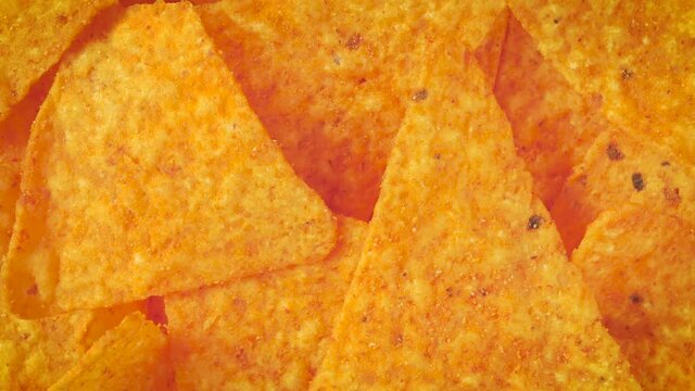tortillas chips rotate on black background. Yellow triangle shaped tortilla chips on black. Mexican salty snack base of corn. Tasty nachos for appetizer. traditional crunchy corn chips.