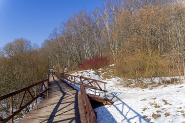 Fototapeta na wymiar A footbridge at the bottom of a ravine in a forest park.