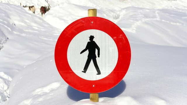 curious road sign submerged by snow depicting a man walking