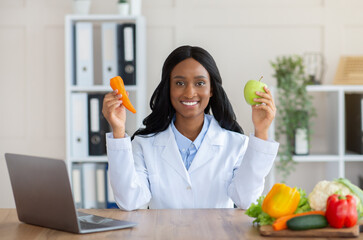 Happy female dietitian holding apple and carrot at medical weight loss clinic