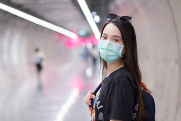 Asian beautiful woman wears black shirt and medical face mask while she walk into Subway tunnel and holds backpack in her hands.  health care,pollution PM2.5 and new normal concept.