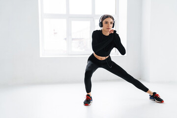 Athletic young sportswoman in headphones working out indoors
