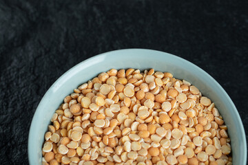 A blue plate with unprepared lentils in a dark background