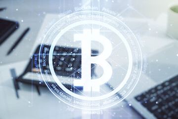 Double exposure of creative Bitcoin symbol hologram on blurry calculator with laptop background. Cryptocurrency concept