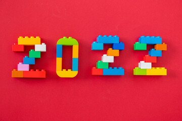 multicolored numbers 2022 from kids constructor set on isolated red background with place for text