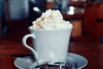 A cup of hot cappuccino with cream topping