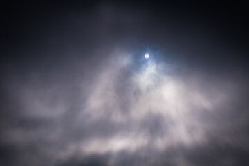 Fototapeta na wymiar Wolkenstimmung mit Nebel mit versteckter Sonne, die etwas hervorblitzt