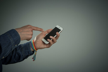 man hand with rainbow bracelet with mobile phone 