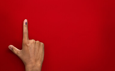 male Indian Voter Hand with voting sign or ink on red background with copy space election commission of India