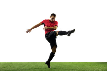 Powerful, flying above the field. Young football, soccer player in action, motion isolated on white background with green grass. Concept of sport, movement, energy and dynamic, healthy lifestyle.