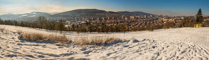 Panorama of city Zlin in valley between hills with typical red brick buildings from snowy meadow
