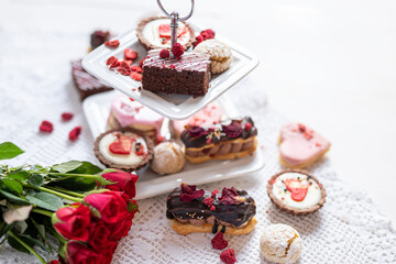 beautiful tasty romantic selection of pink chocolate love heart shape cakes for wedding, mothers day,  valentines day, spring flower biscuits tartlet and rose petals 