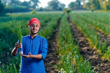 Young indian farmer holding onion crop in hand at agriculture field
