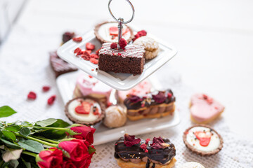 beautiful tasty romantic selection of pink chocolate love heart shape cakes for wedding, mothers day,  valentines day, spring flower biscuits tartlet and rose petals 