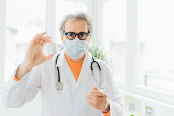 Portrait of senior doctor holding a bottle of pills