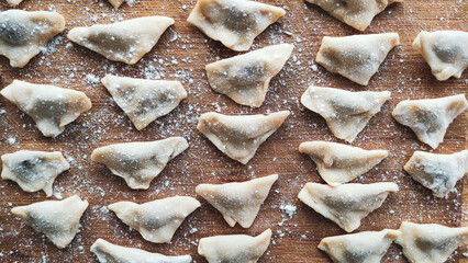 Traditional Turkish manti. Famous Turkish food manti on the wooden table. Close up of handmade manti. Traditional Turkish dumplings. Dumplings with meat onion and spice Turkish dumplings recipe