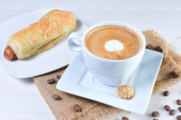 Cup of Colombian coffee, accompanied by baked bakery on white wooden background