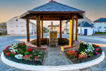 View of religious cross in Spanish road and village, under a pergola decorated with colorful...
