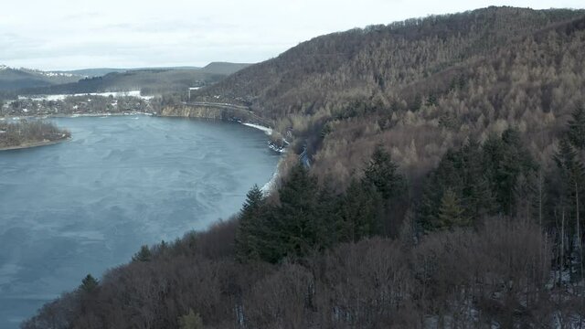 Drone Aerial views of the Keller National Park in Winter. The barrier lake Edersee is partly frozen. The Ederstausee is located in Hesse near the town Waldeck in Germany, Europe.