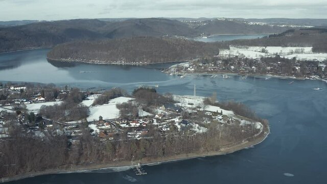 Drone Aerial views of the Keller National Park in Winter. The barrier lake Edersee is partly frozen. The Ederstausee is located in Hesse near the town Waldeck in Germany, Europe.