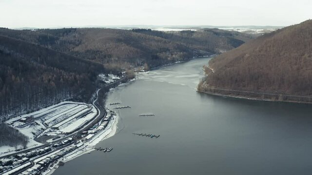 Drone Aerial views of the Keller National Park in Winter. The barrier lake Edersee is partly frozen. The Ederstausee is located in Hesse near the town Waldeck in Germany, Europe.
