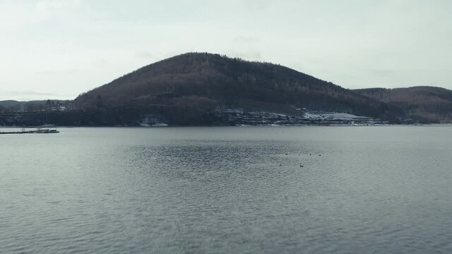Drone Aerial views of the Keller National Park in Winter. The barrier lake Edersee is partly frozen. The Ederstausee is located in Hesse near the town Waldeck in Germany, Europe.