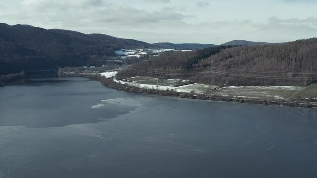 Drone Aerial views of the Keller National Park in Winter. The barrier lake Edersee is partly frozen. The Ederstausee is located in Hesse near the town Waldeck in Germany, Europe.