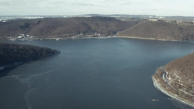 Drone Aerial views of the Keller National Park in Winter. The barrier lake Edersee is partly frozen. The Ederstausee is located in Hesse near the town Waldeck in Germany, Europe.