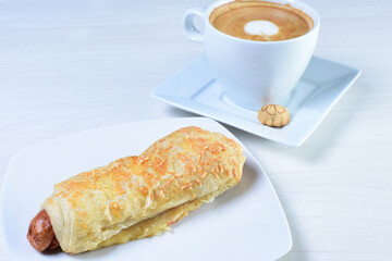 Cup of Colombian coffee, accompanied by baked bakery on white wooden background