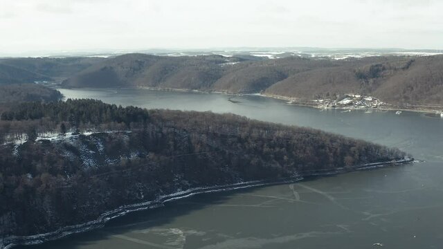 Drone Aerial views of the Keller National Park in Winter. The barrier lake Edersee is partly frozen. The Ederstausee is located in Hesse near the town Waldeck in Germany, Europe.