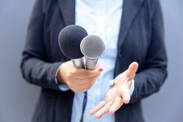 Journalist or TV reporter holding microphone and making media interview. Broadcast journalism concept.