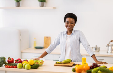 Happy African Woman Posing In Kitchen Cooking Healthy Vegetable Dish