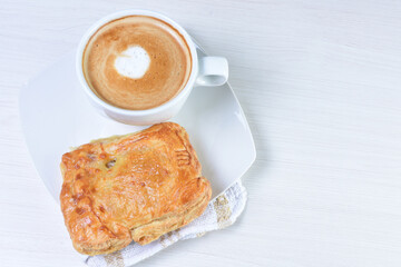 Cup of Colombian coffee, accompanied by baked bakery on white wooden background