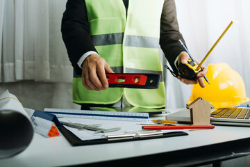 Two colleagues discussing data working and tablet, laptop with on on architectural project at construction site at desk in office