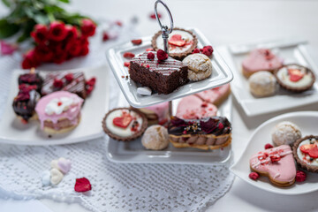 beautiful tasty romantic selection of pink chocolate love heart shape cakes for wedding, mothers day,  valentines day, spring flower biscuits tartlet and rose petals 